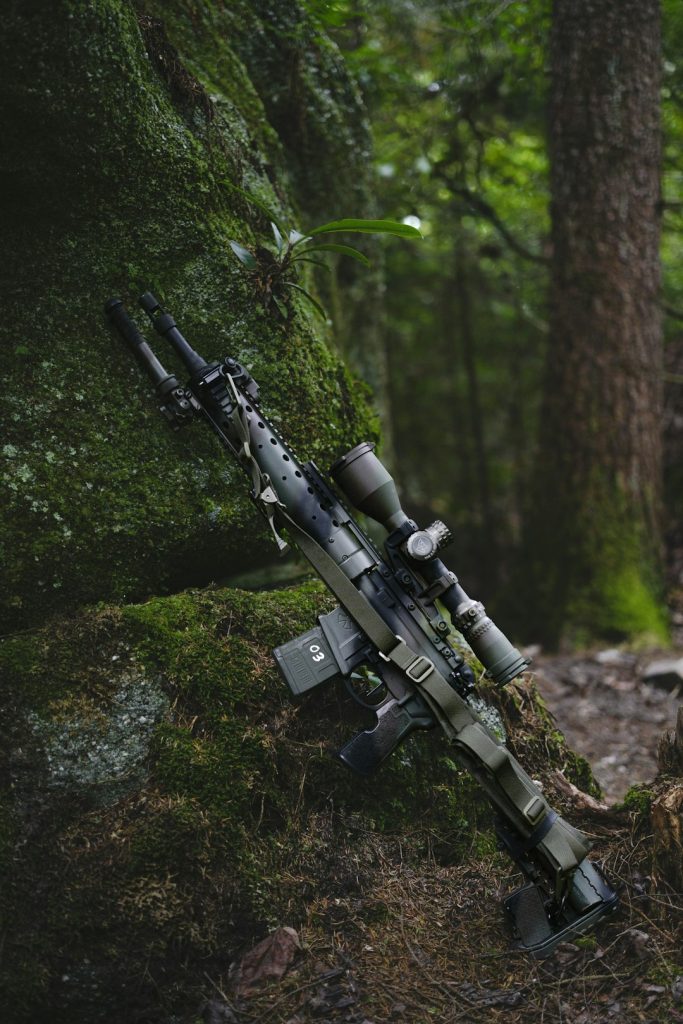 a-rifle-rests-against-a-mossy-forest-rock-gnd5edejkqq