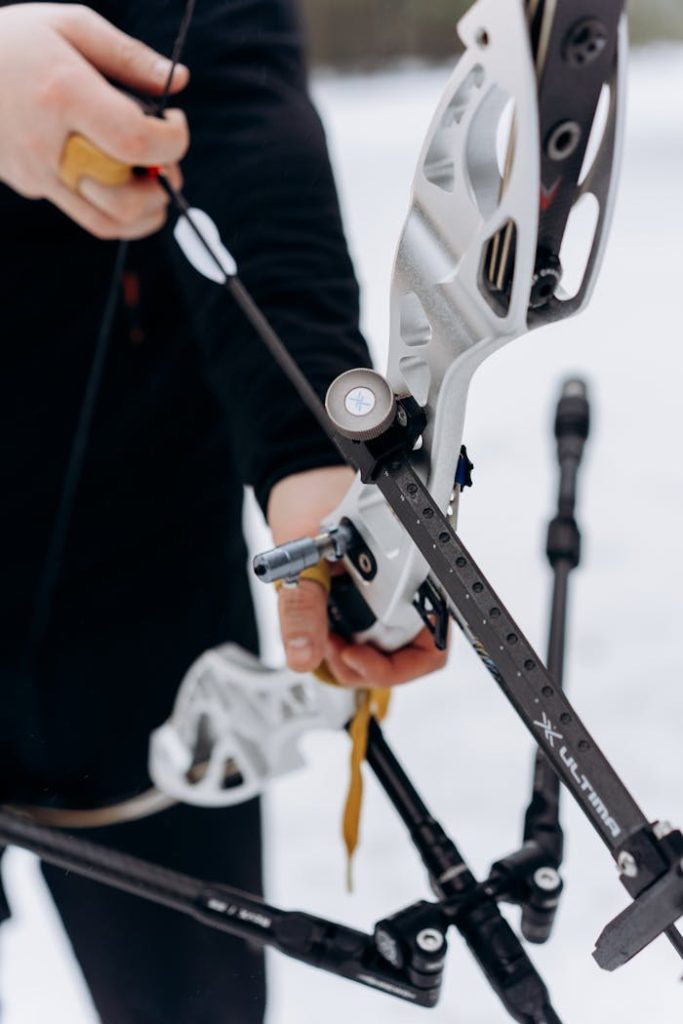 Close-up of an archer handling bow and arrows in a snowy landscape.